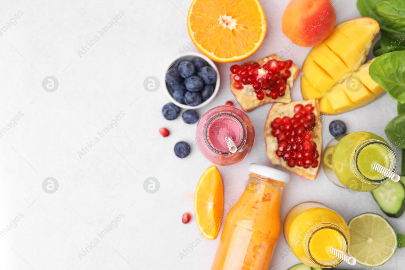 Photo of Glass bottles of tasty smoothies and different products on white table, flat lay. Space for text