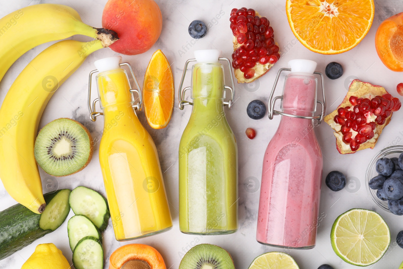 Photo of Glass bottles of tasty smoothies and different products on white marble table, flat lay