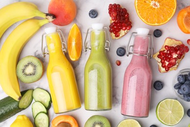 Glass bottles of tasty smoothies and different products on white marble table, flat lay