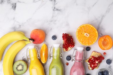 Glass bottles of tasty smoothies and different products on white marble table, flat lay. Space for text