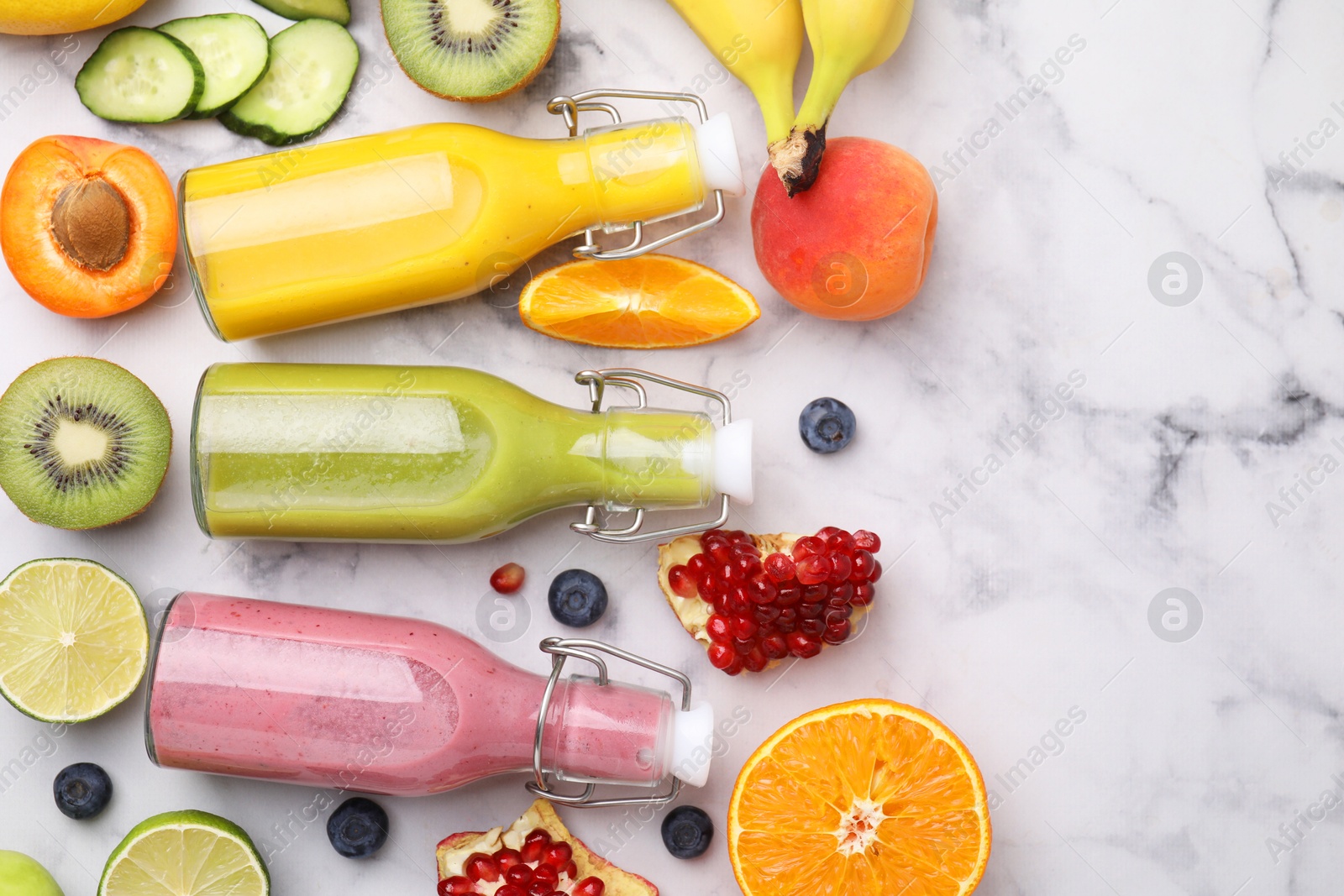 Photo of Glass bottles of tasty smoothies and different products on white marble table, flat lay. Space for text