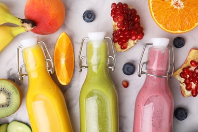 Glass bottles of tasty smoothies and different products on white marble table, flat lay