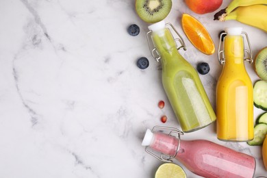 Glass bottles of tasty smoothies and different products on white marble table, flat lay. Space for text