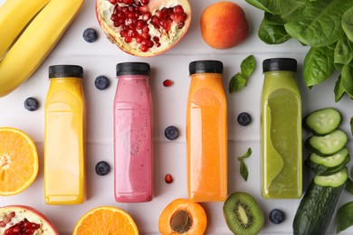 Photo of Glass bottles of tasty smoothies and different products on white tiled table, flat lay