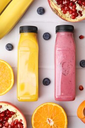 Glass bottles of tasty smoothies and different products on white tiled table, flat lay