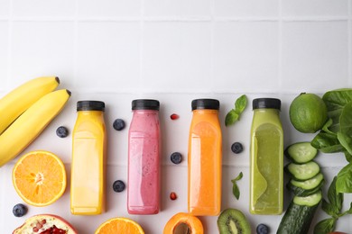 Photo of Glass bottles of tasty smoothies and different products on white tiled table, flat lay. Space for text