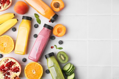 Glass bottles of tasty smoothies and different products on white tiled table, flat lay. Space for text