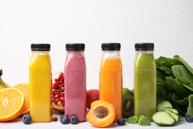 Glass bottles of tasty smoothies and different products on white tiled table