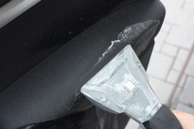 Photo of Man cleaning car door with vacuum cleaner outdoors, closeup