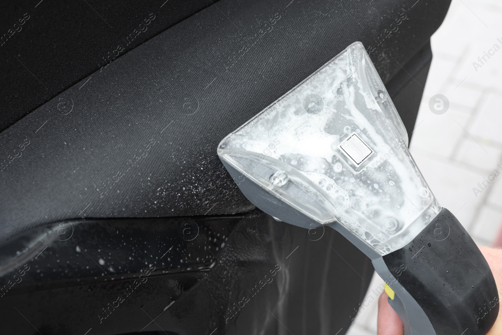 Photo of Man cleaning car door with vacuum cleaner outdoors, closeup