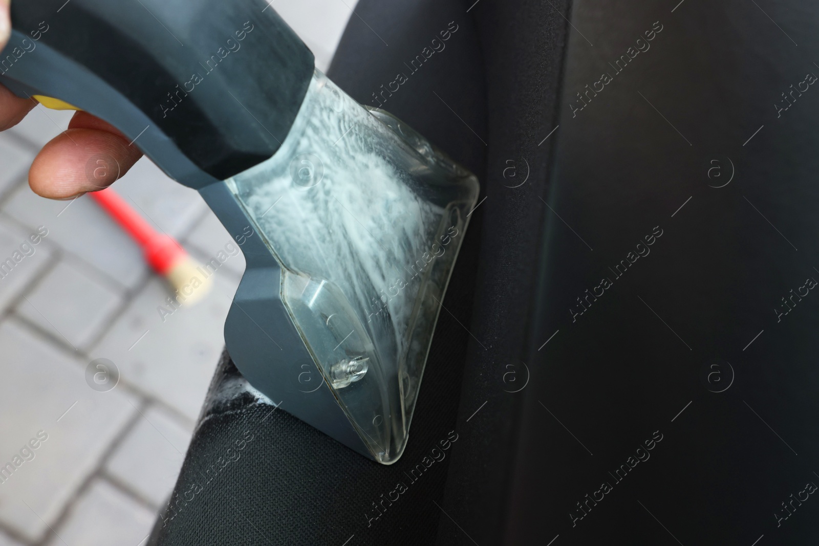 Photo of Man cleaning car door with vacuum cleaner outdoors, closeup