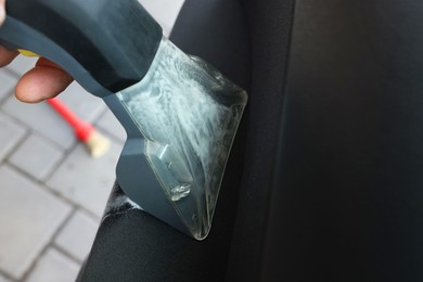 Photo of Man cleaning car door with vacuum cleaner outdoors, closeup