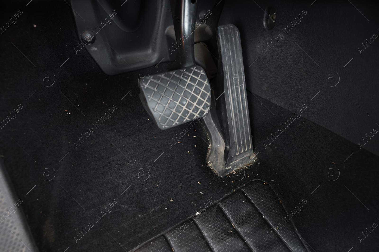 Photo of Black soft car floor mat in auto, closeup