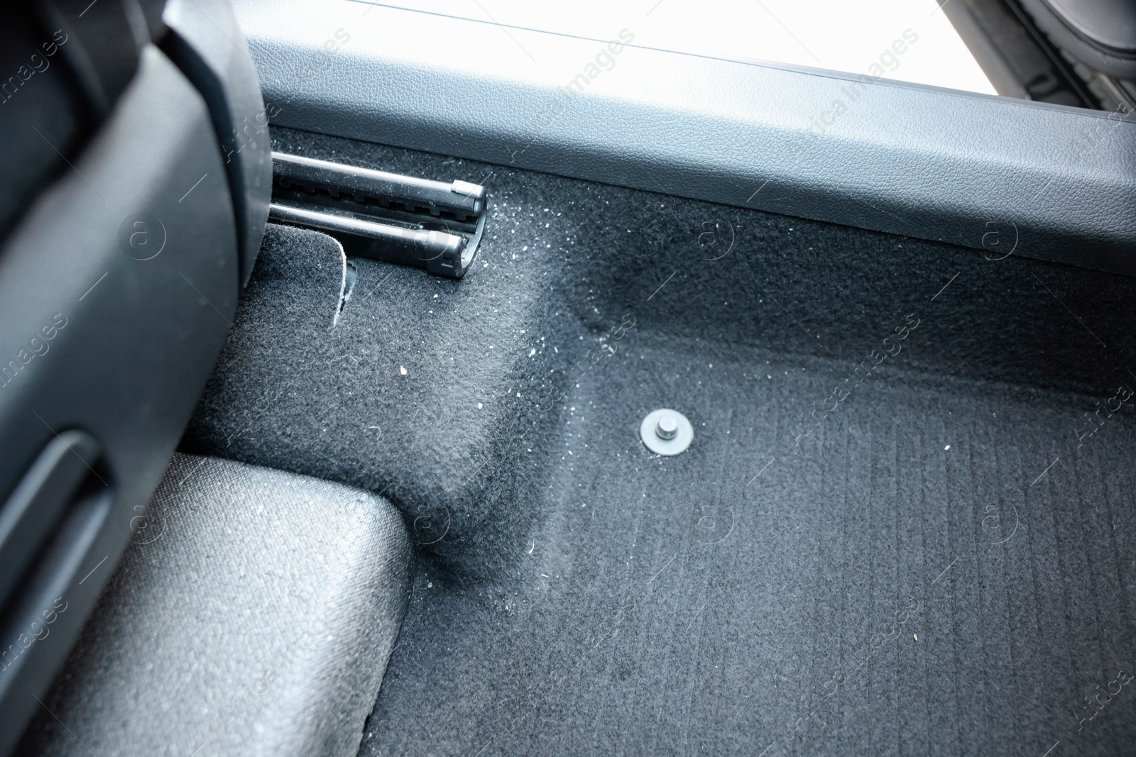 Photo of Black soft car floor mat in auto, closeup