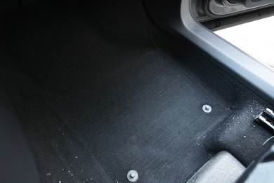 Photo of Black soft car floor mat in auto, closeup