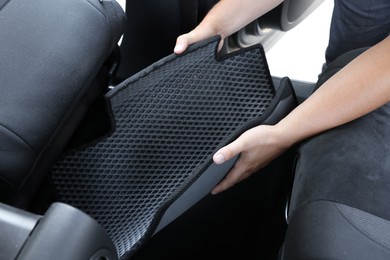 Photo of Man taking grey rubber car mat from auto, closeup