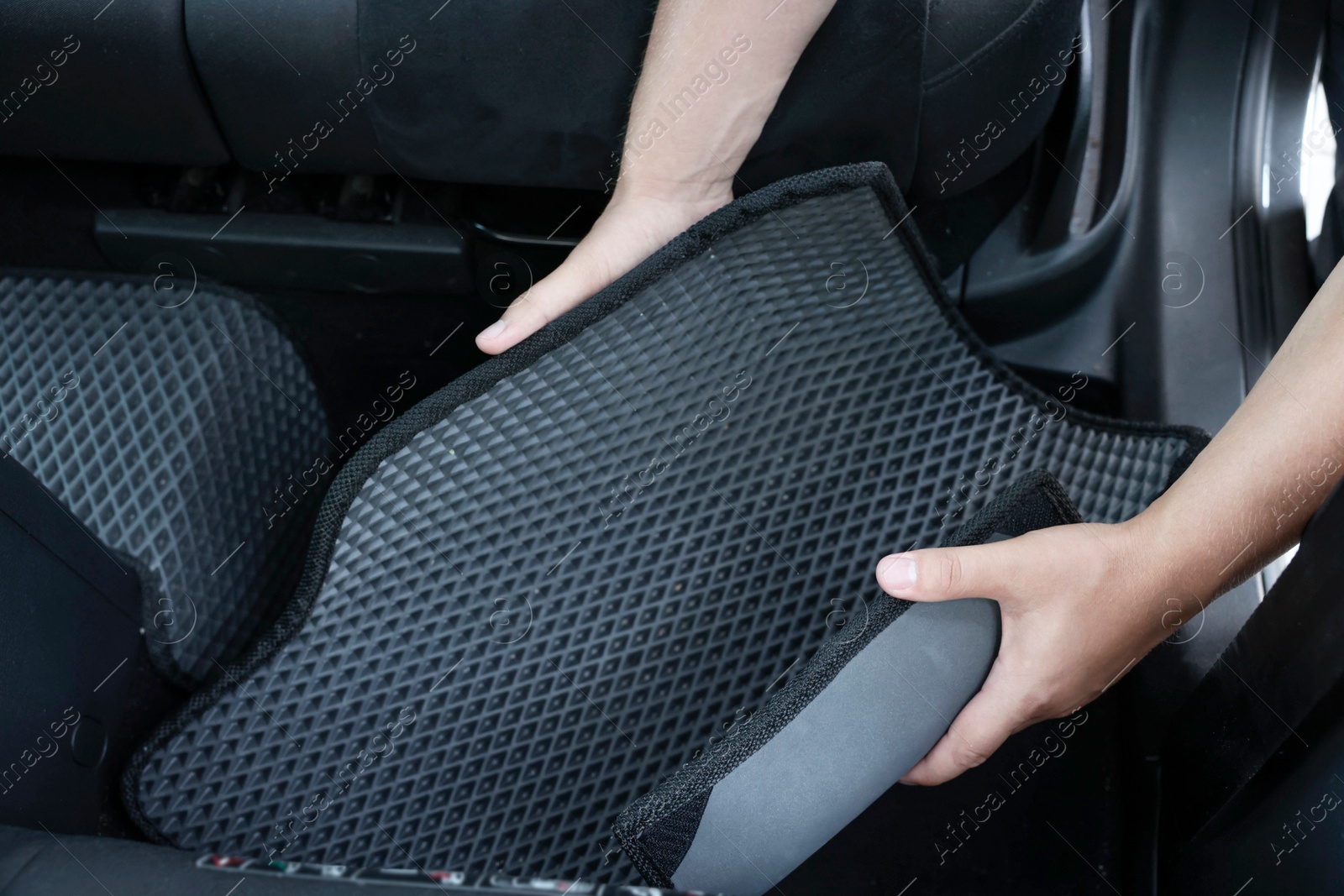 Photo of Man taking grey rubber car mat from auto, closeup