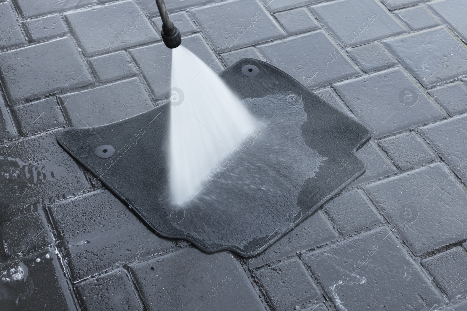 Photo of Washing car mat with high pressure water jet outdoors, closeup