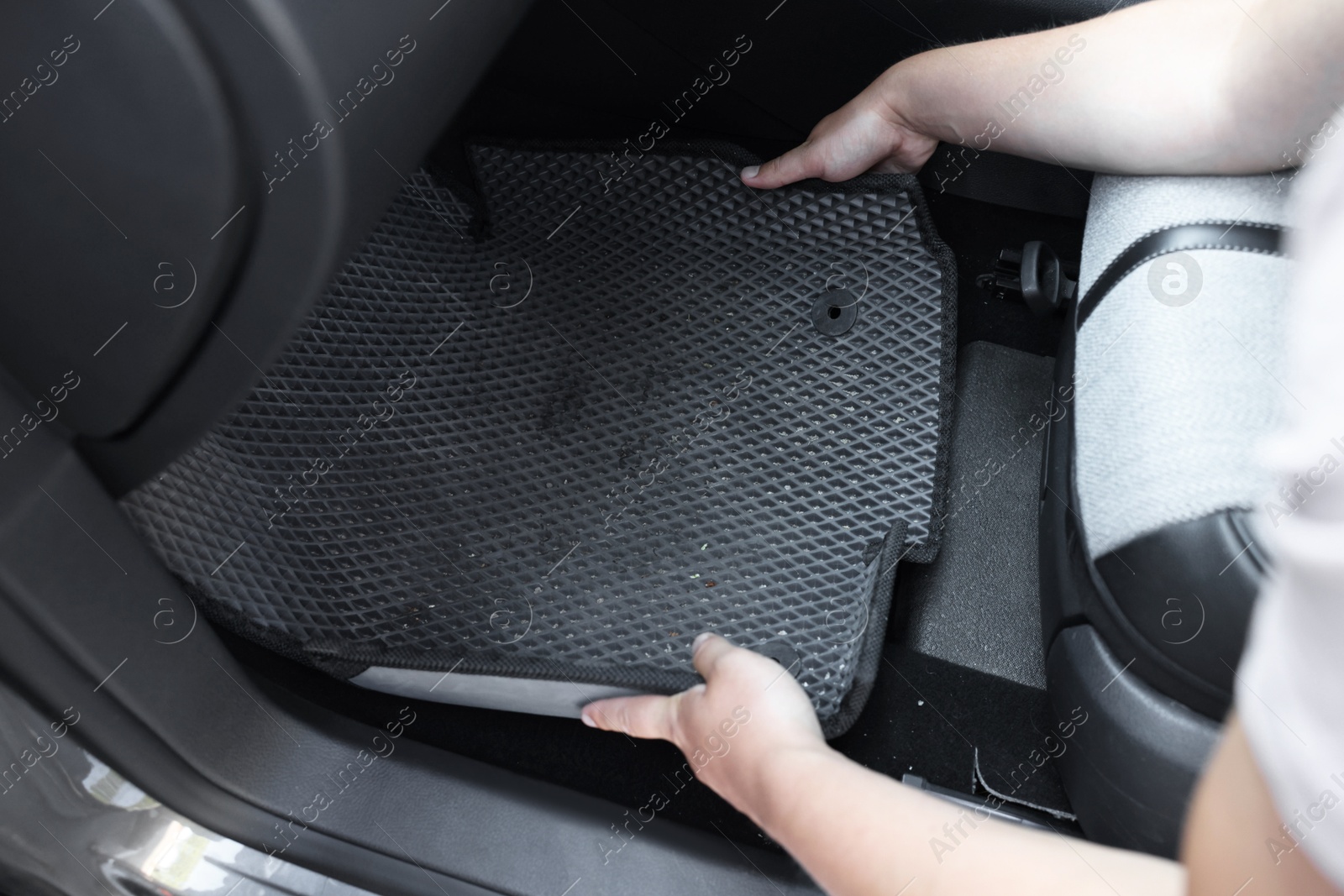 Photo of Man taking grey rubber car mat from auto, closeup