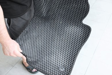 Photo of Man with dirty rubber car mat indoors, closeup