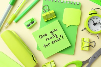 Photo of Paper note with question Are You Ready For Exam and stationery on pale yellow background, flat lay