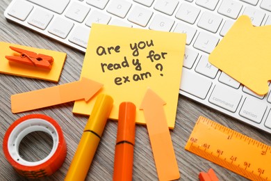 Note with question Are You Ready For Exam and stationery on wooden desk, closeup