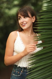 Photo of Portrait of smiling woman near palm leaves outdoors