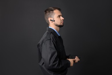 Photo of Security guard in uniform with earpiece and gun on black background