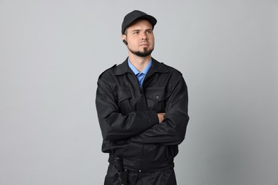 Photo of Security guard in uniform with earpiece on grey background