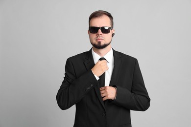 Photo of Young bodyguard in suit and sunglasses on grey background