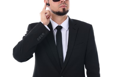 Photo of Young bodyguard in suit using earpiece on white background, closeup