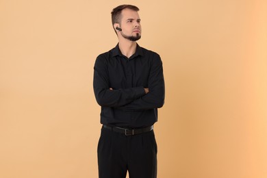 Photo of Young bodyguard with earpiece on beige background