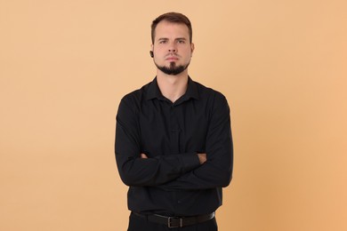 Young bodyguard with earpiece on beige background