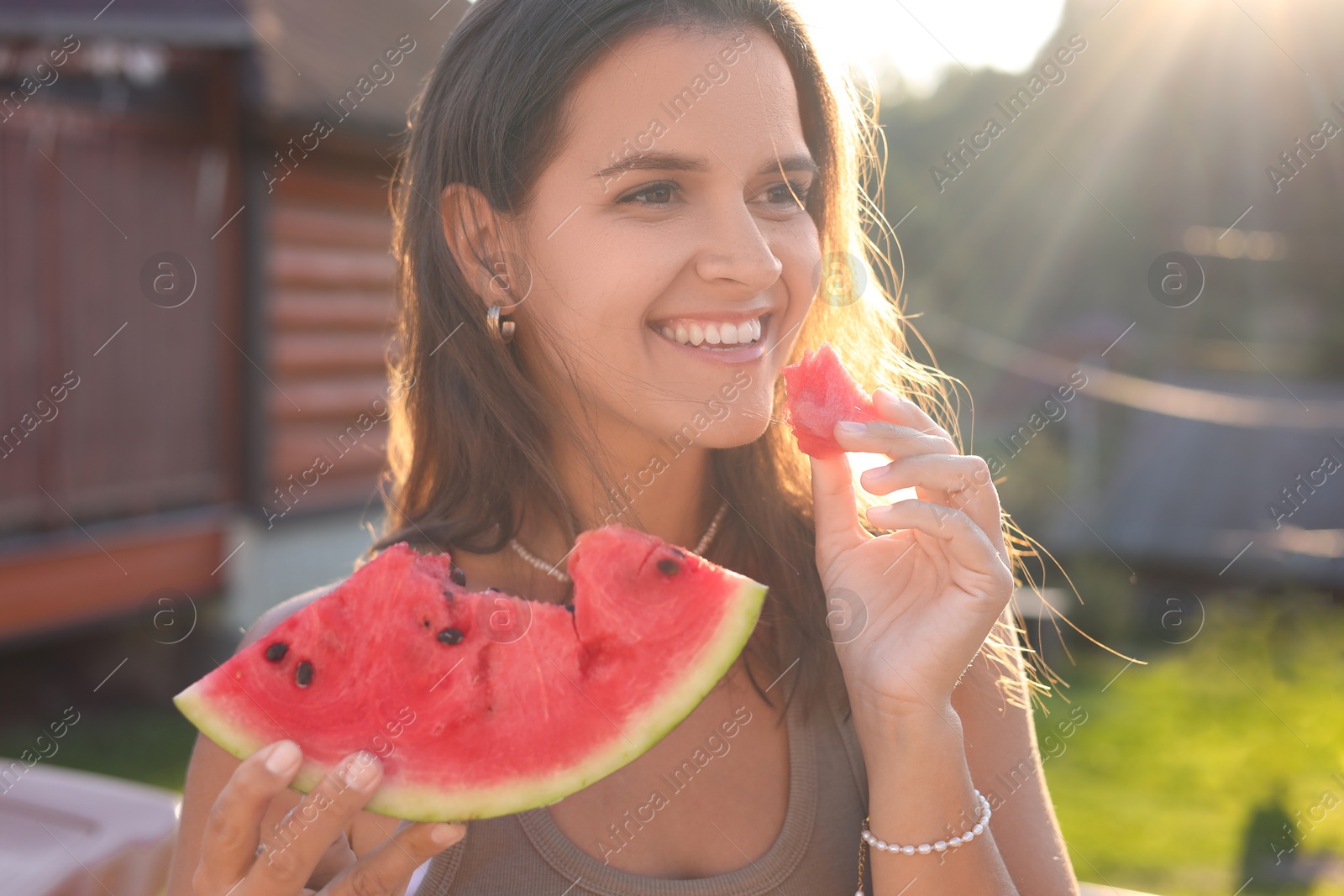 Photo of Woman eating fresh juicy watermelon outdoors on sunny day