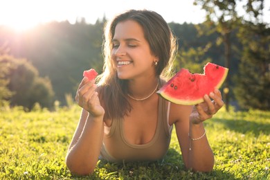 Photo of Happy woman with slice of juicy watermelon on green grass outdoors