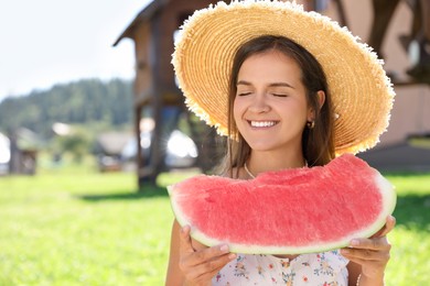 Happy woman with slice of juicy watermelon outdoors, space for text