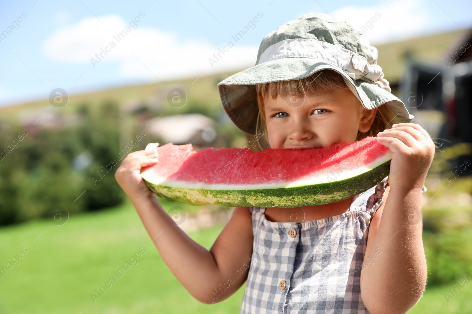 Photo of Cute little girl eating juicy watermelon outdoors