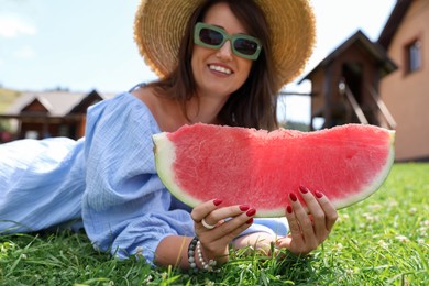 Photo of Woman with slice of juicy watermelon on green grass outdoors