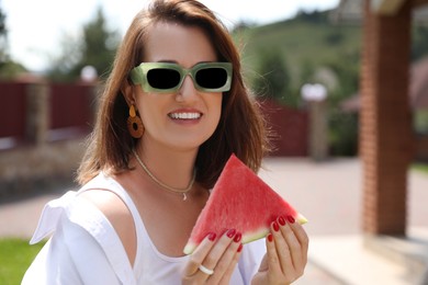 Photo of Happy woman with slice of juicy watermelon outdoors, space for text