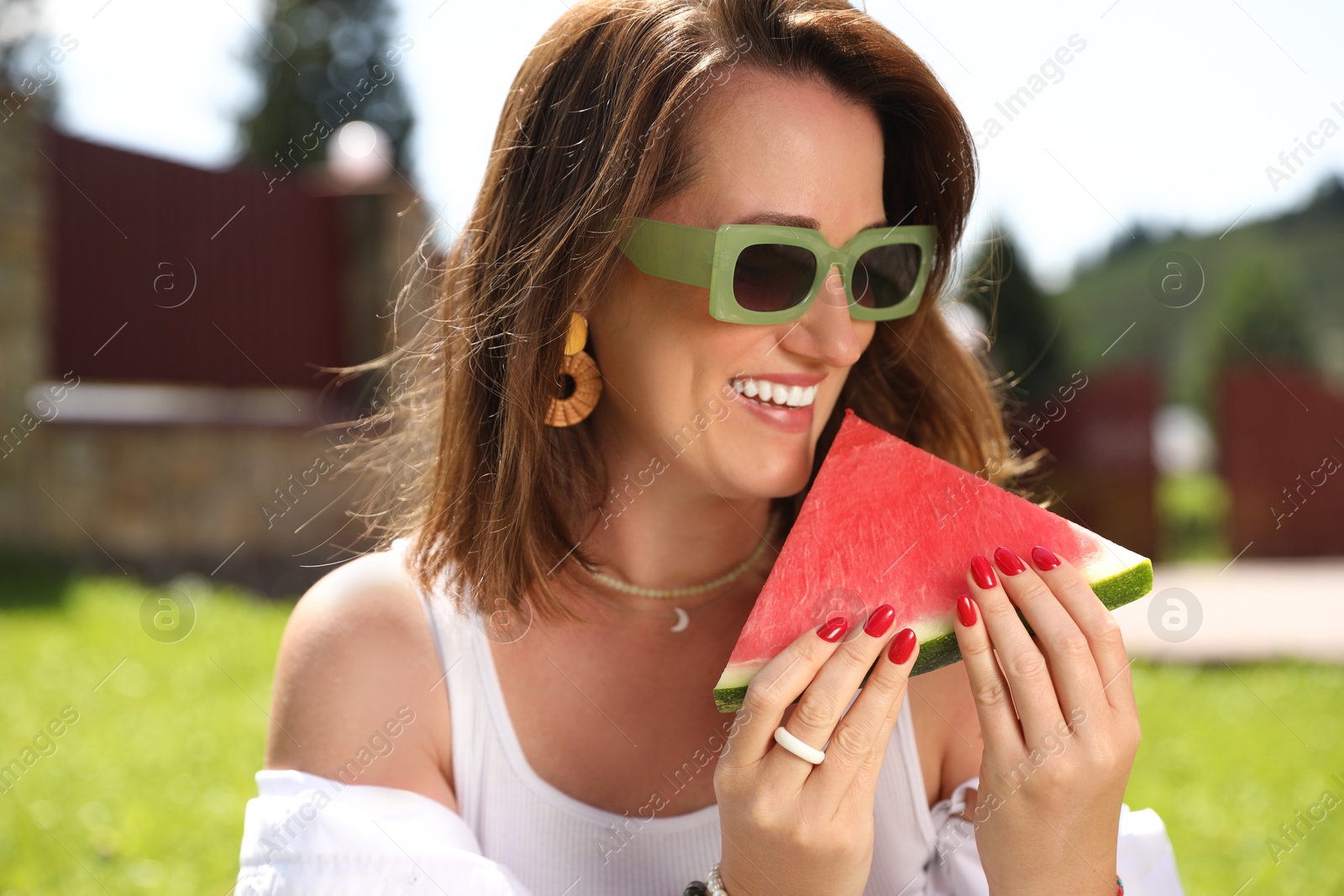 Photo of Happy woman holding slice of juicy watermelon outdoors