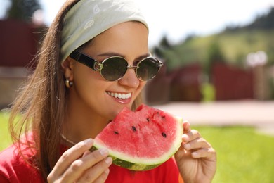 Happy woman in sunglasses eating juicy watermelon outdoors