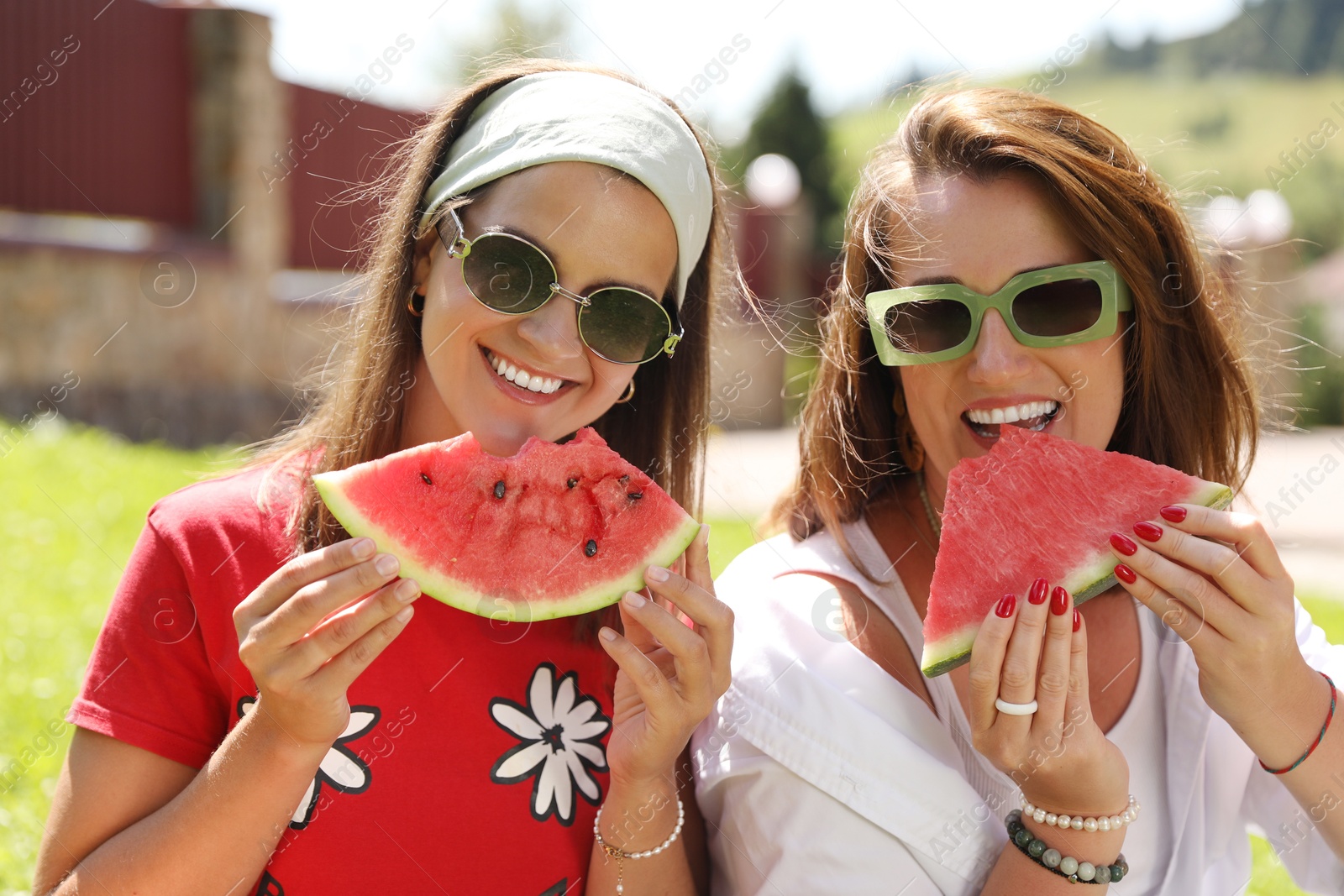 Photo of Happy women eating fresh juicy watermelon outdoors