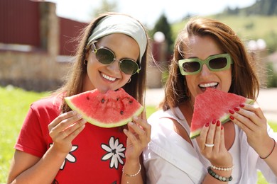 Happy women eating fresh juicy watermelon outdoors