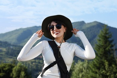 Smiling woman in sunglasses with backpack in beautiful mountains