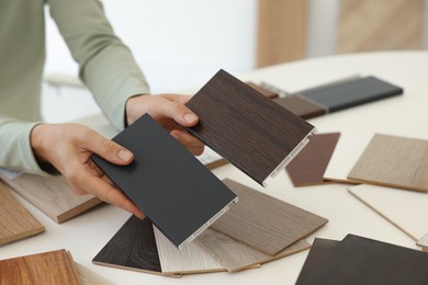 Photo of Woman choosing wooden flooring among different samples at table, closeup