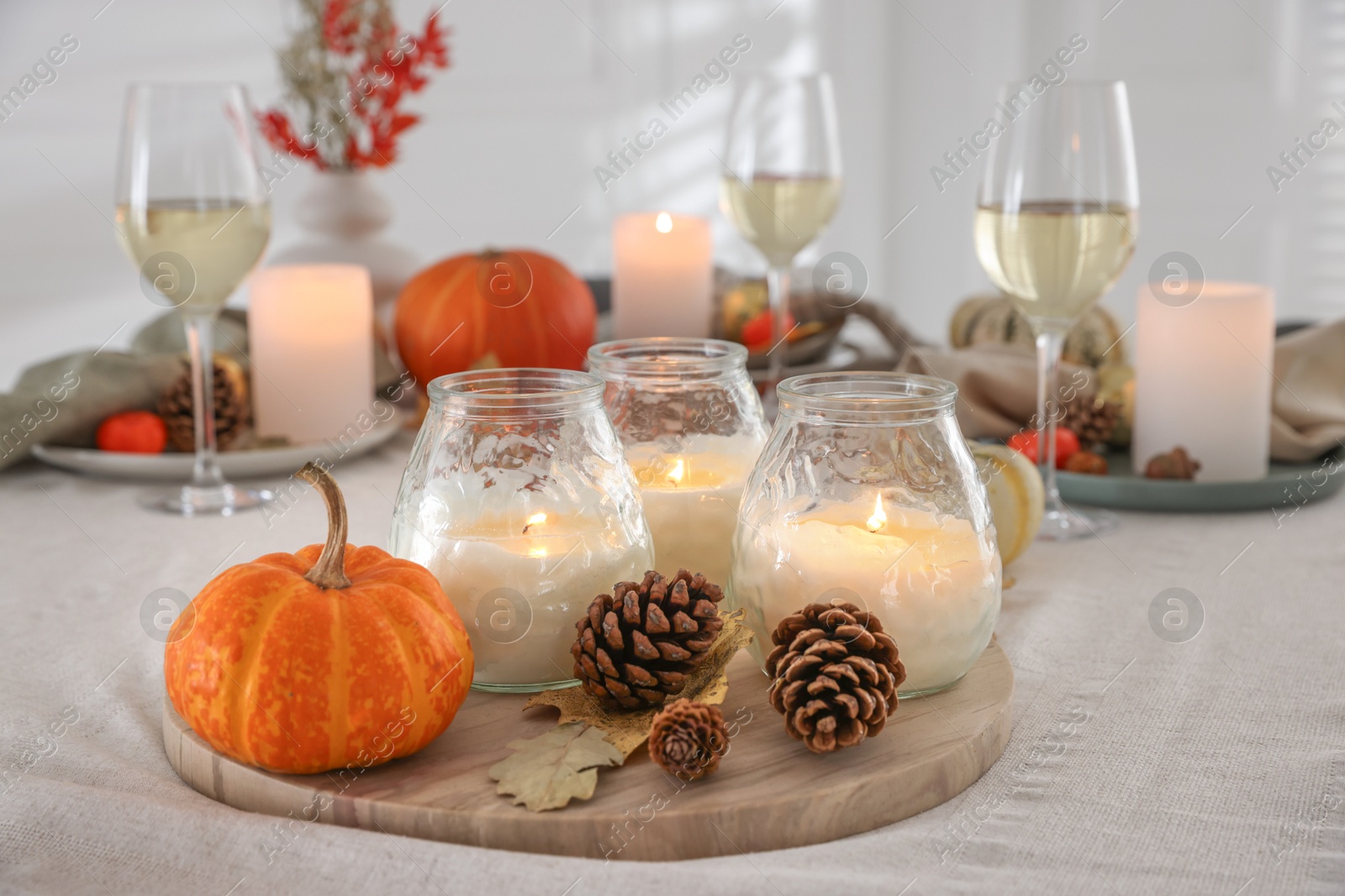 Photo of Burning candles and autumn decor on table indoors