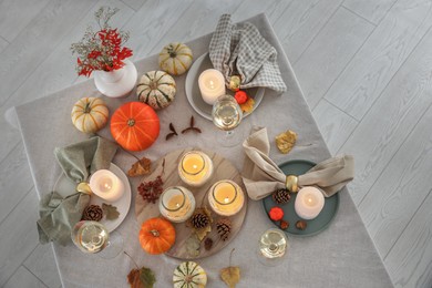 Photo of Autumn place setting with burning candles, glasses of wine and decor on table indoors, top view