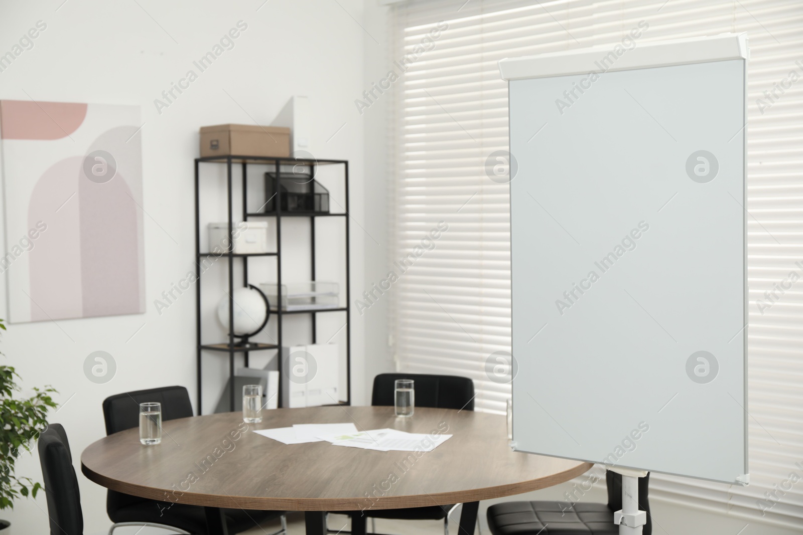 Photo of Flip chart, wooden table and chairs in conference room. Mockup for design