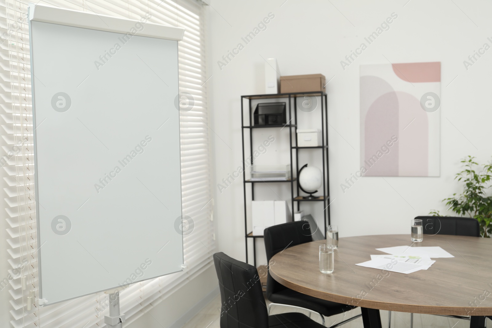 Photo of Flip chart, wooden table and chairs in conference room. Mockup for design