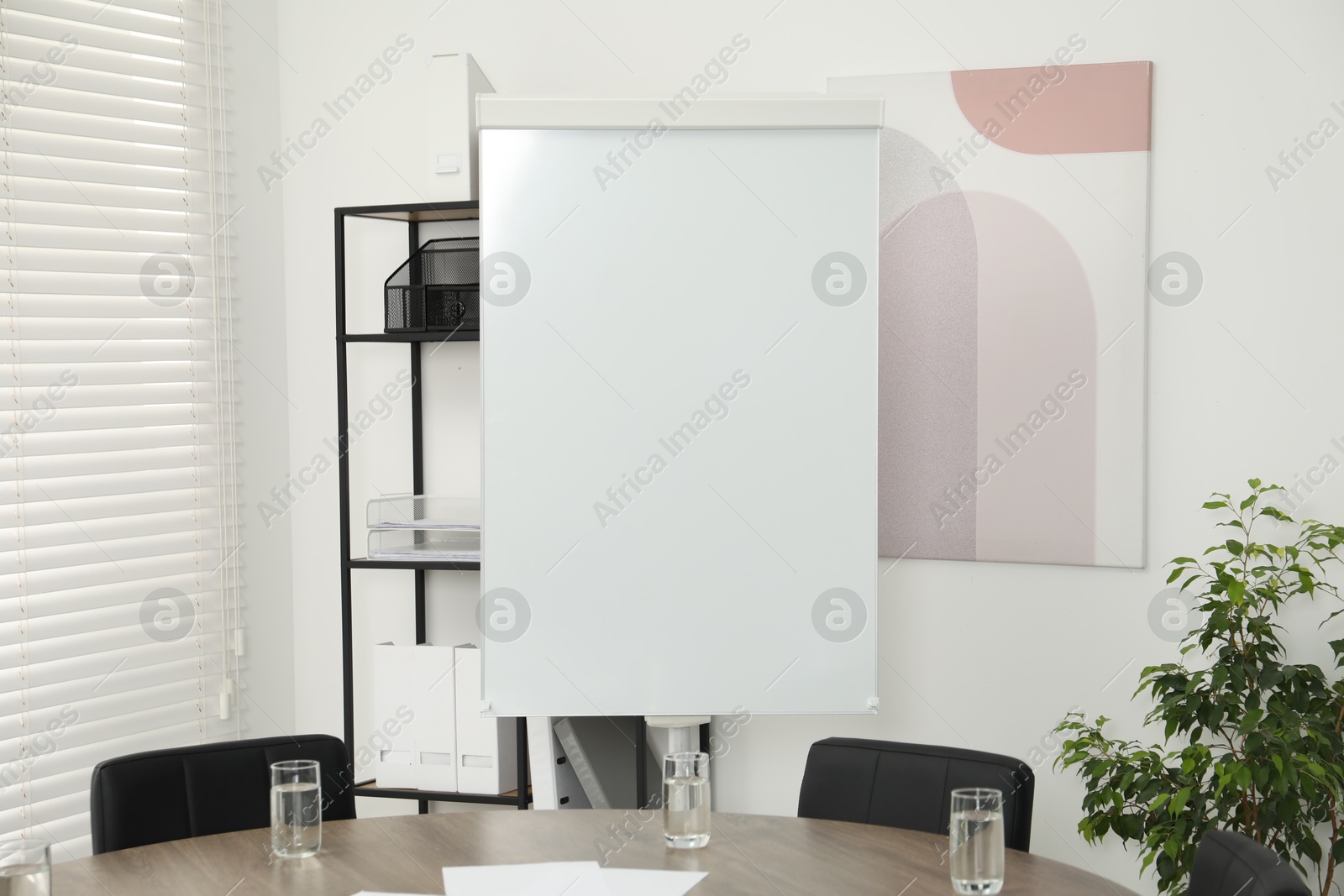 Photo of Flip chart, wooden table and chairs in conference room. Mockup for design